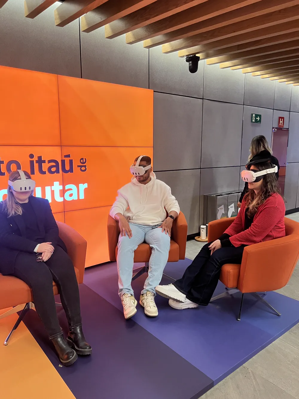 Três pessoas em poltronas laranja usando óculos VR