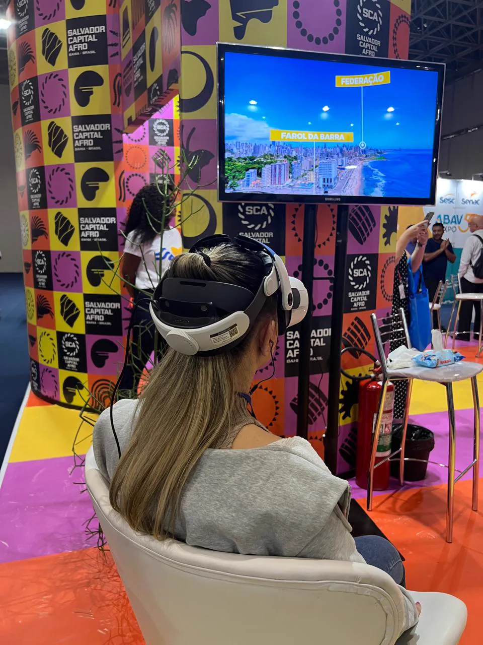 Visitante sentada usando óculos VR no estande Salvador Capital Afro